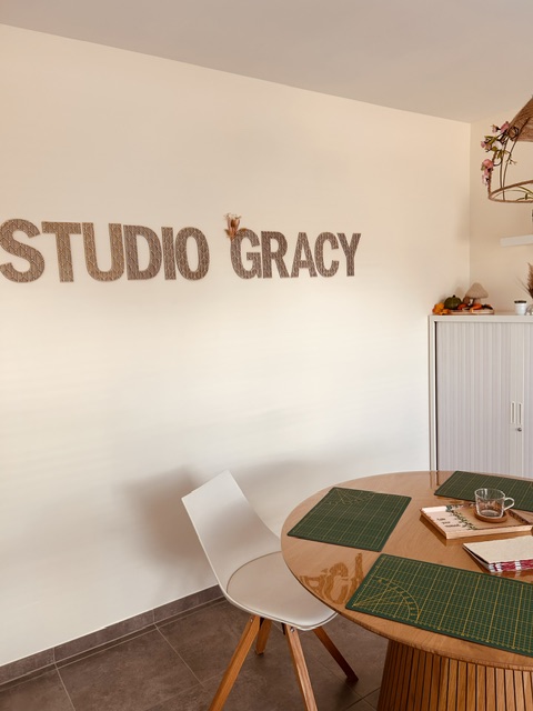 Workshopruimte met de letters Studio Gracy op de muur en een houten tafel met groene snijmatten